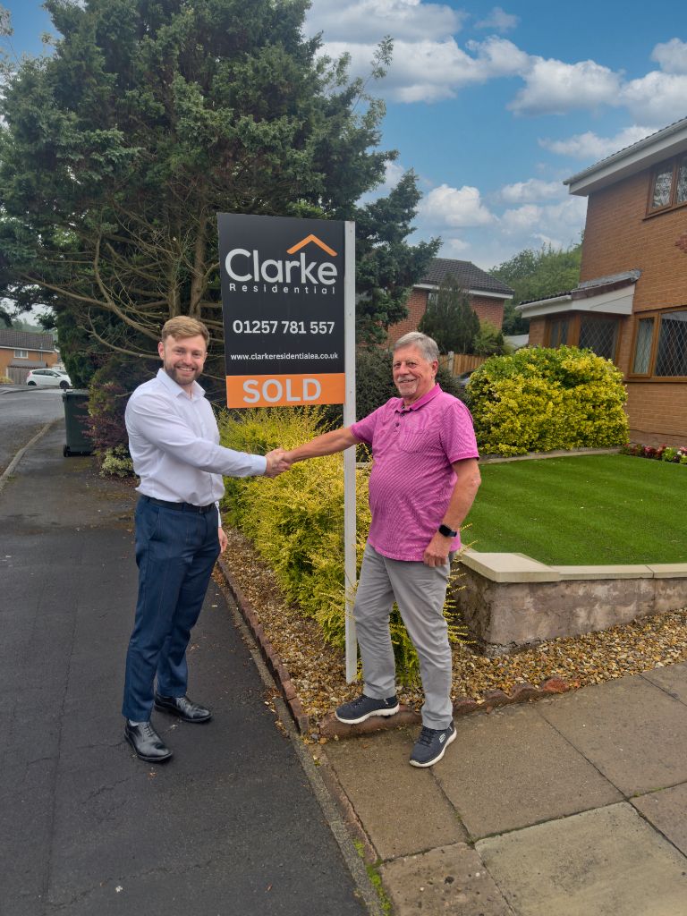 Callum Clarke shaking hands with a happy client next to a Clarke Residential SOLD board
